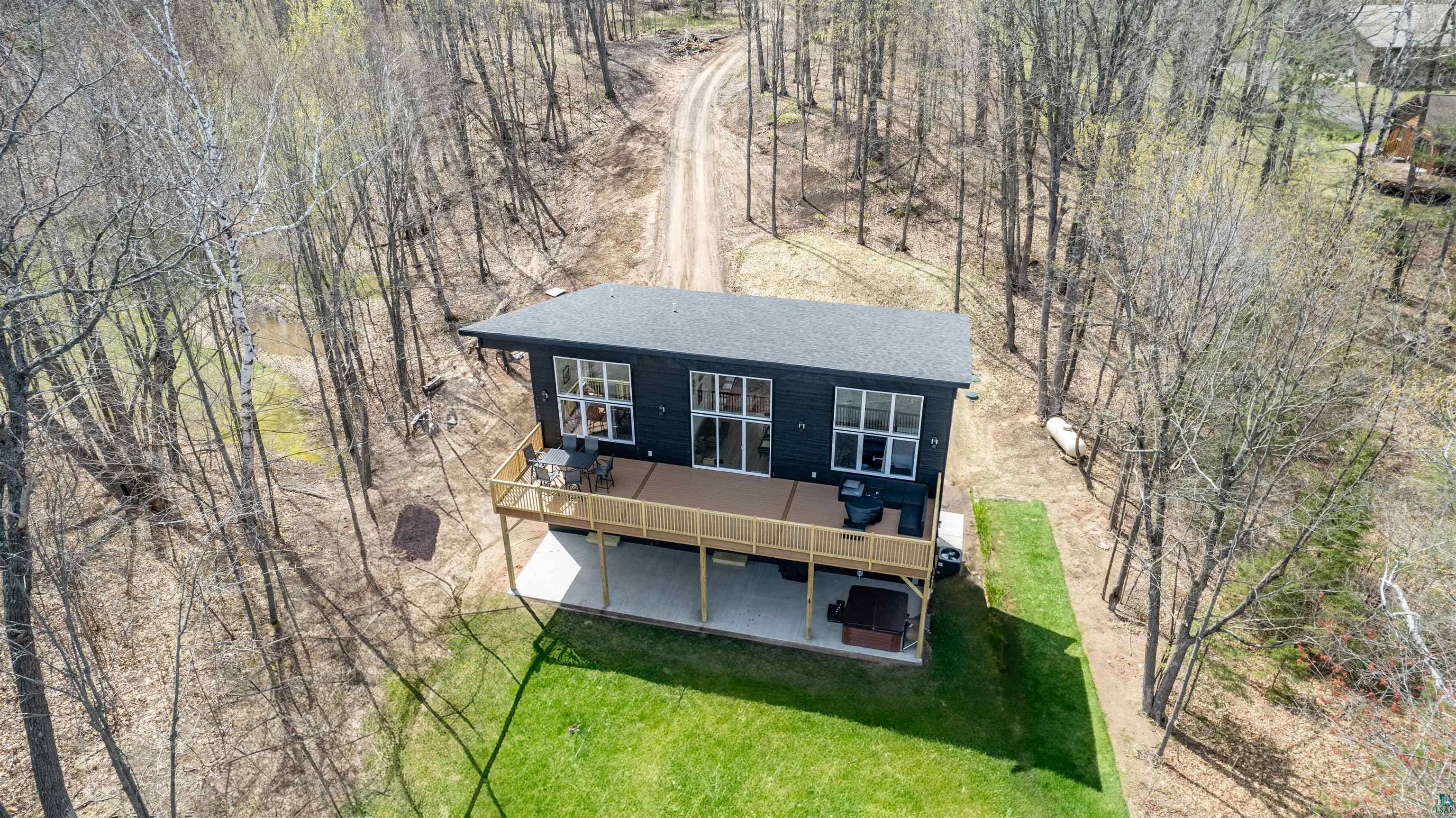 2000 West Chub Lake Road Carlton, MN 55718 - Photo 2 of 30 Modern dark-paneled home with a broad upper-level deck, lower-level patio, and surrounding wooded landscape