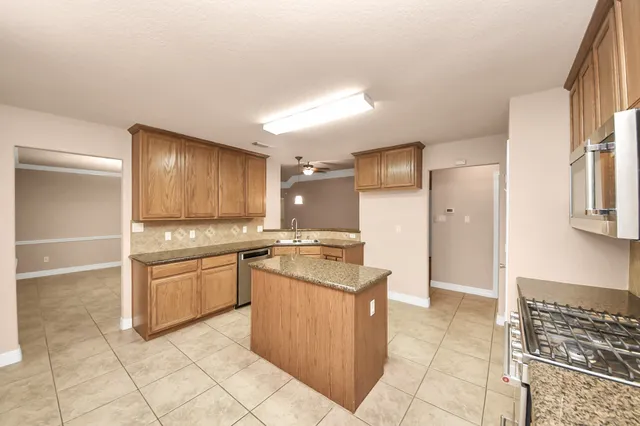 a kitchen with stainless steel appliances granite countertop a refrigerator and a stove top oven
