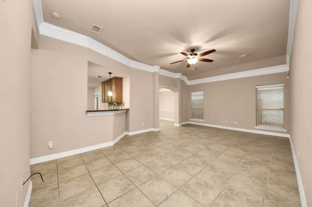 an empty room with chandelier fan and windows