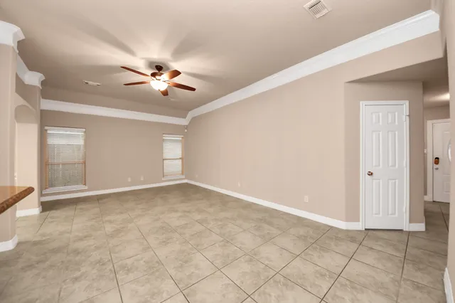 a view of an empty room with chandelier fan