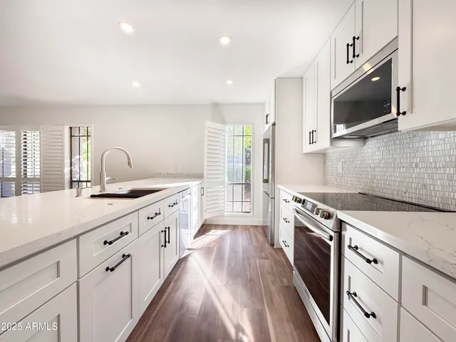 a large kitchen with cabinets stainless steel appliances a sink and wooden floor