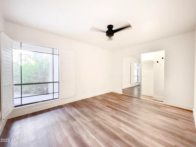 a view of empty room with wooden floor and fan