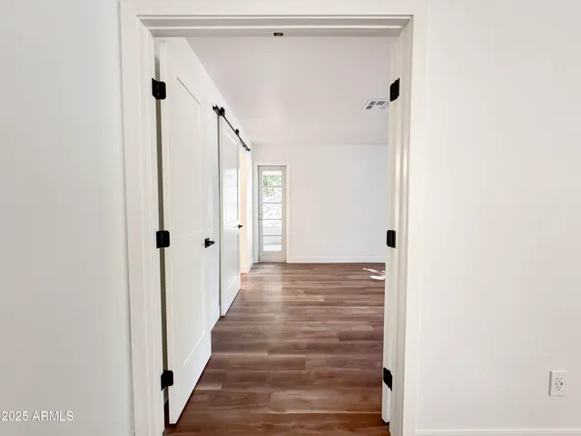 an empty room with wooden floor fan and windows