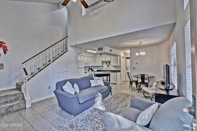 a living room with furniture kitchen view and a chandelier