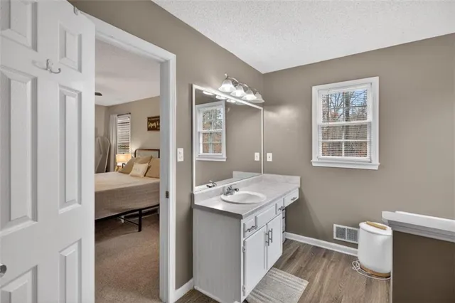 a en suite bathroom with a granite countertop sink a mirror and a bathtub
