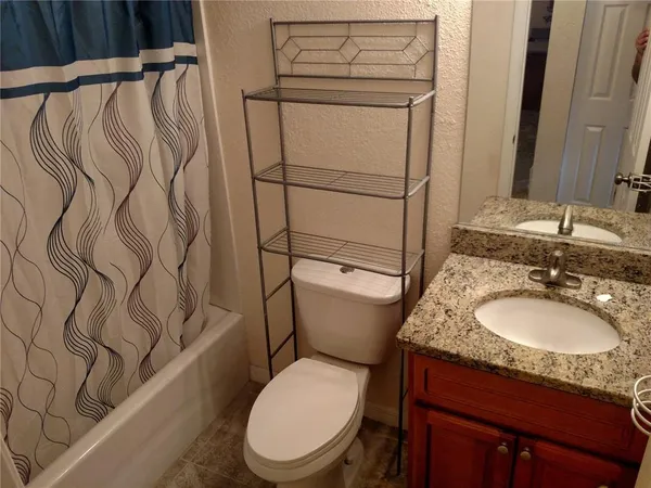 a bathroom with a granite countertop toilet sink and mirror