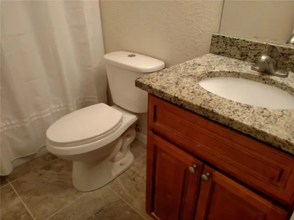 a bathroom with a granite countertop toilet and a sink