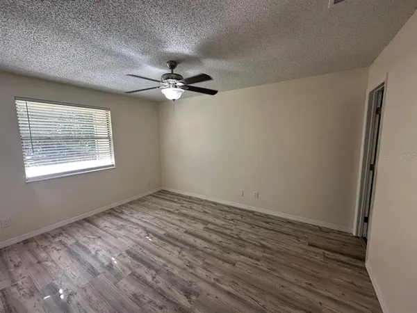 a view of empty room with wooden floor and fan