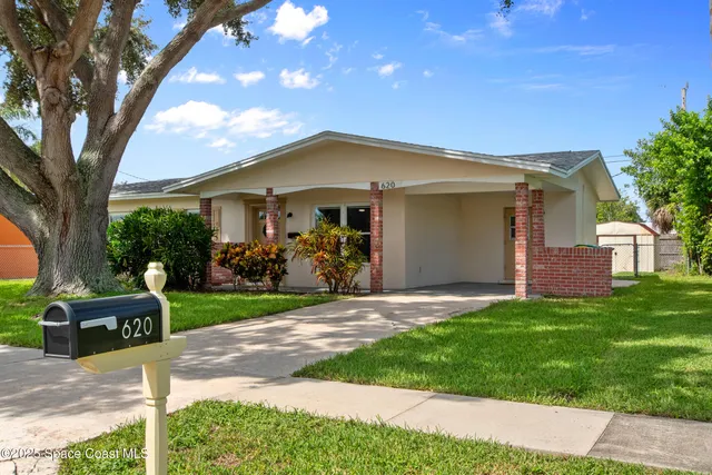 a front view of a house with a garden and trees