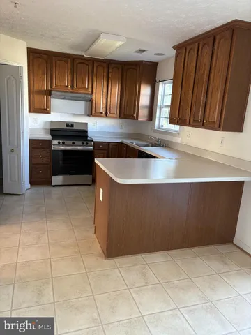 a kitchen with granite countertop a stove a microwave a sink and cabinets