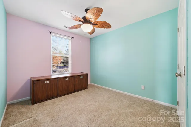 an empty room with a window and a chandelier fan