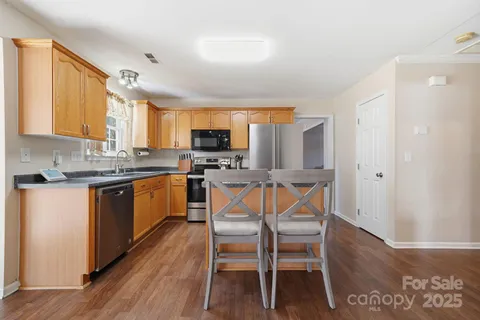 a kitchen with stainless steel appliances granite countertop wooden floors a stove a microwave a center island and a window