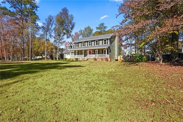 a view of a house with a big yard and large trees