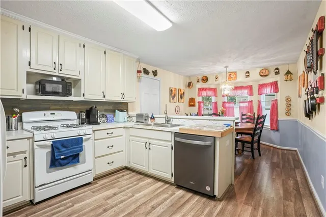 a kitchen with stainless steel appliances granite countertop a stove and white cabinets with wooden floor