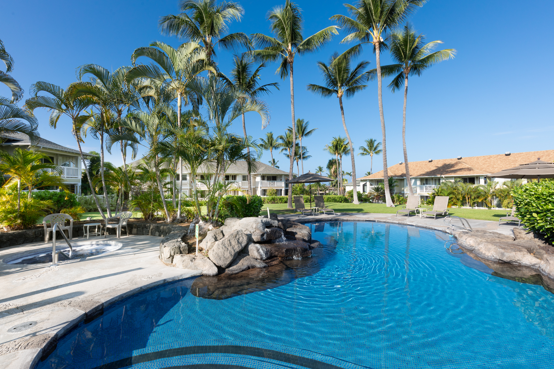 75-6009 Alii Drive, Unit A4 Kailua-Kona, HI 96740 - Photo 24 of 27 a view of a swimming pool with a table and chairs