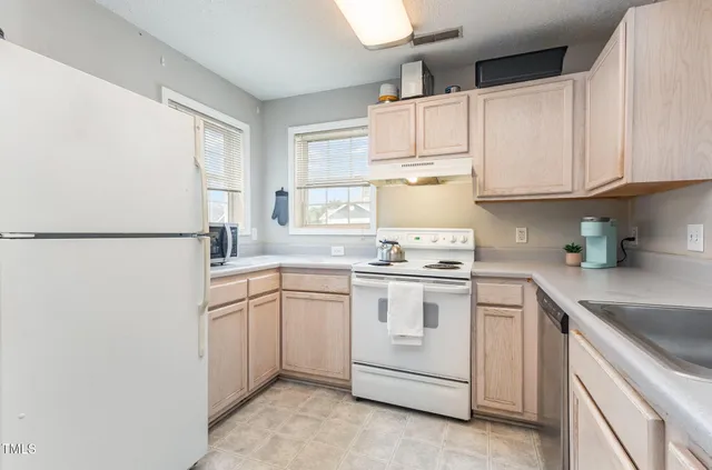 a kitchen with granite countertop white cabinets sink and appliances
