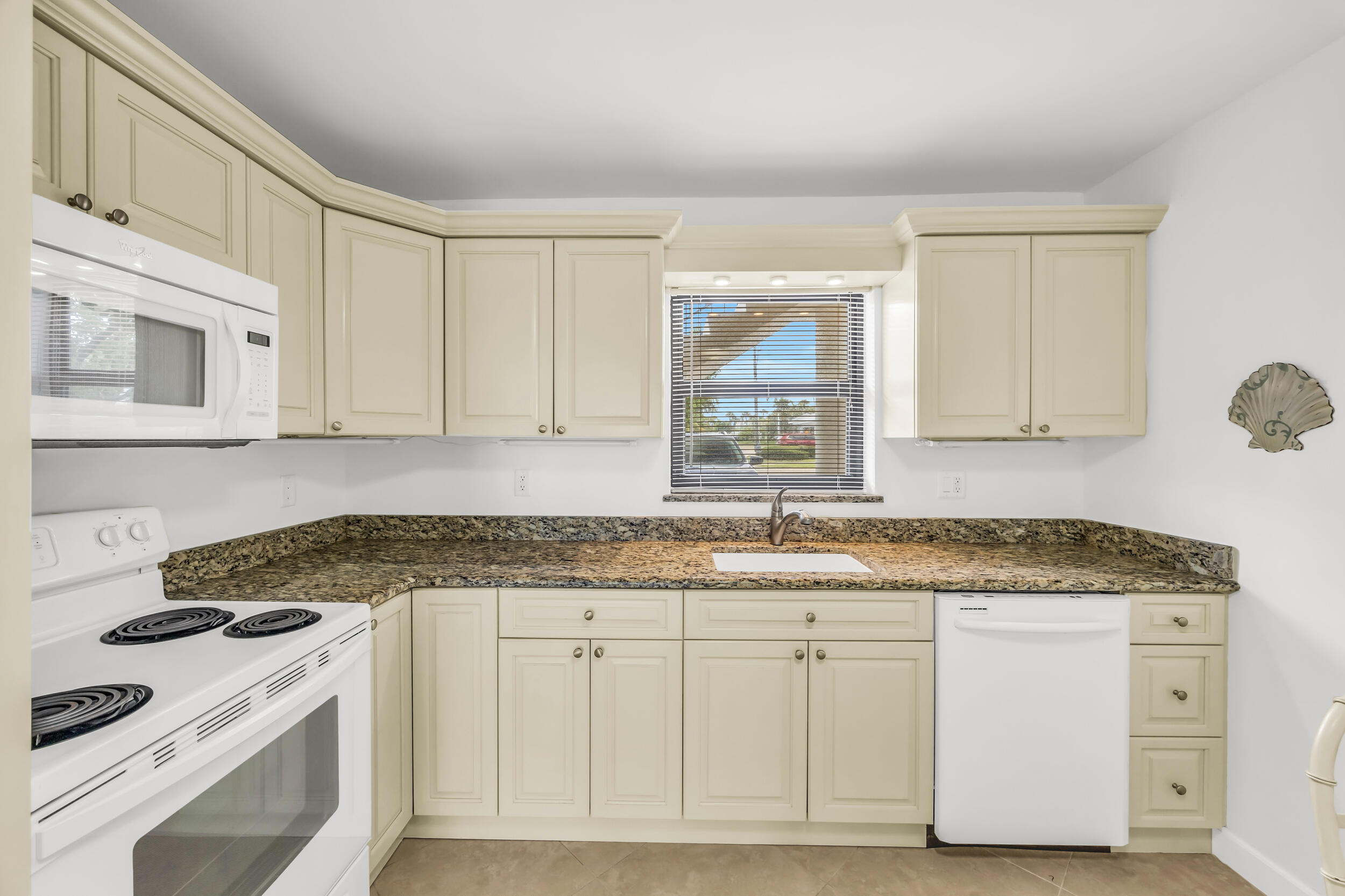 755 Saturn Street, Unit G101 Jupiter, FL 33477 - Photo 6 of 31 a kitchen with granite countertop white cabinets and white appliances