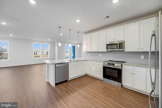 a large kitchen with cabinets wooden floor and stainless steel appliances
