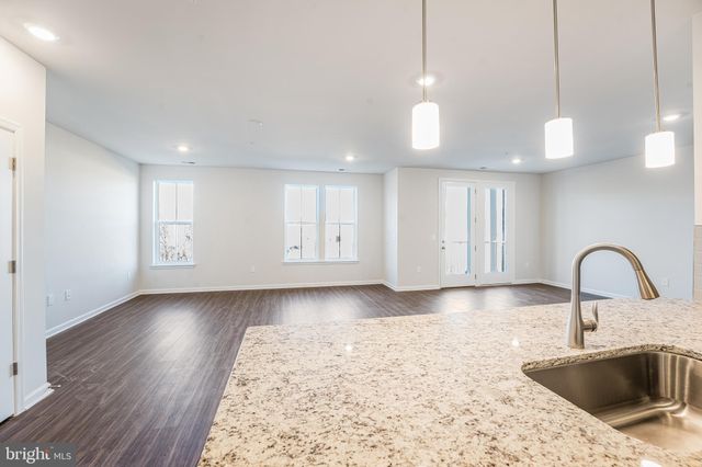 a kitchen with stainless steel appliances granite countertop a sink a stove and a wooden floor