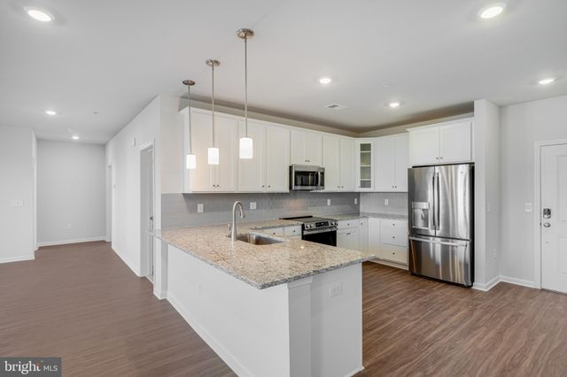 a kitchen with stainless steel appliances granite countertop a refrigerator a sink dishwasher a stove and a refrigerator with wooden floor