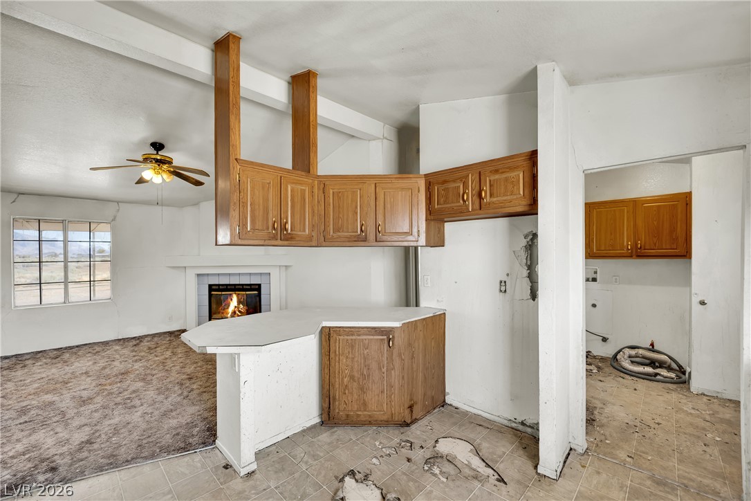 4361 Maple Road Pahrump, NV 89048 - Photo 13 of 46 A corner kitchen with a breakfast bar, wood cabinetry, and an adjoining living area with a fireplace.