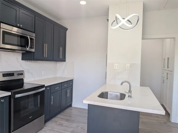 a kitchen with stainless steel appliances granite countertop a sink and a stove top oven with wooden floor