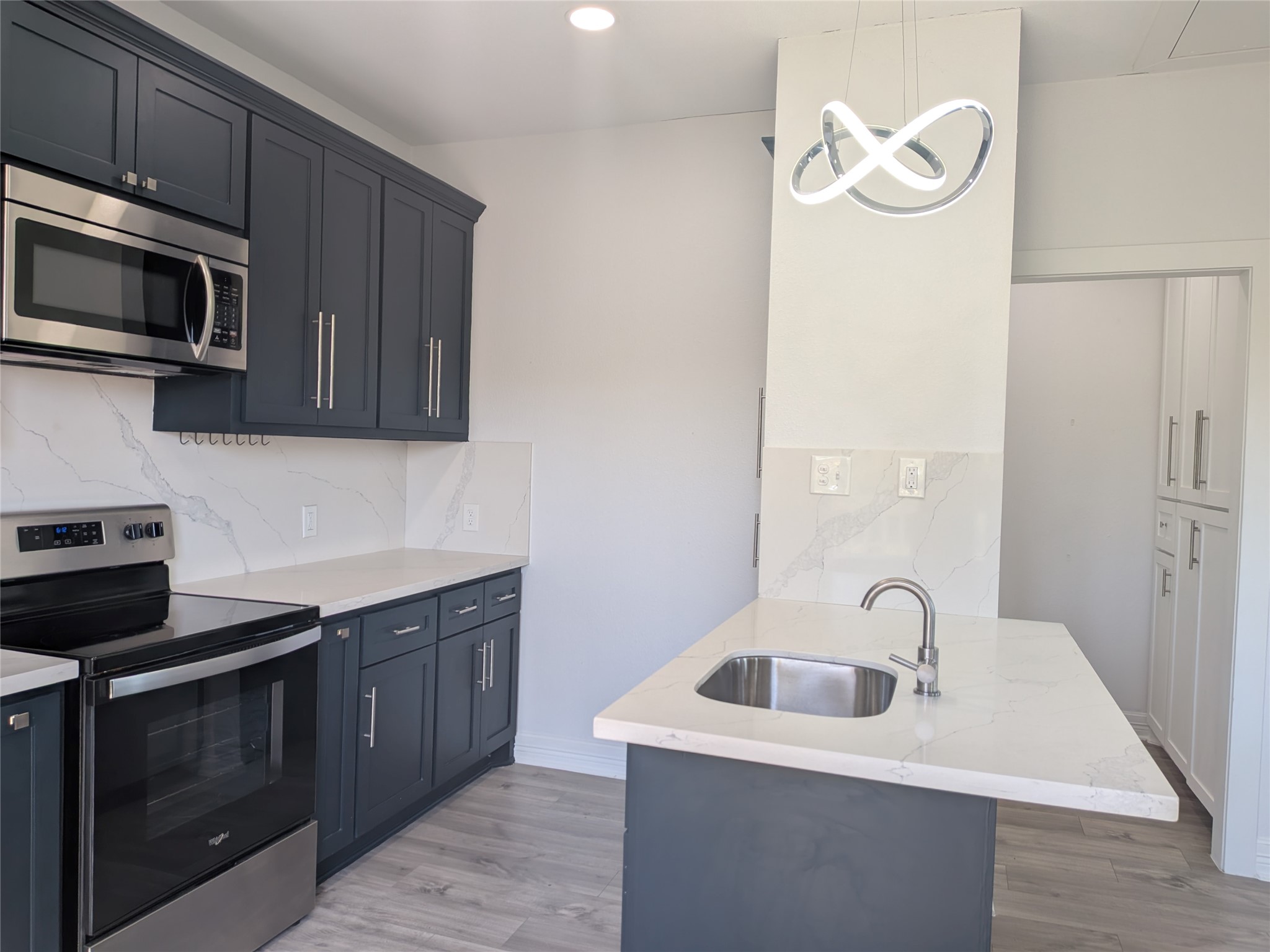 4711 Rusk Street, Unit A Houston, TX 77023 - Photo 9 of 19 a kitchen with stainless steel appliances granite countertop a sink and a stove top oven with wooden floor