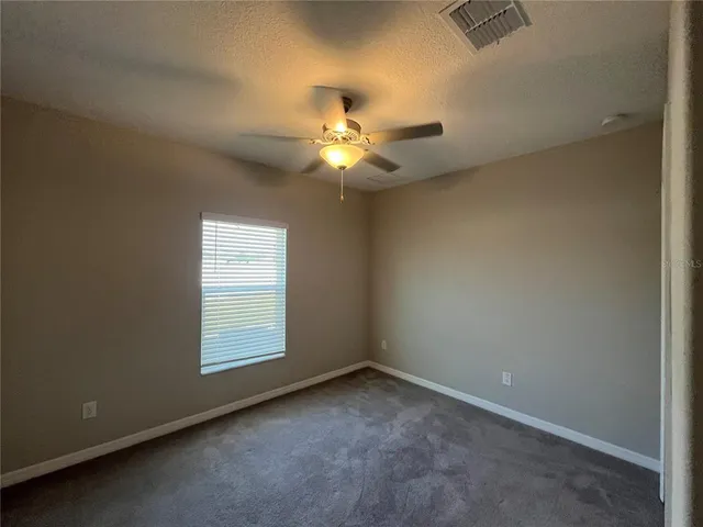 an empty room with a ceiling fan and a window