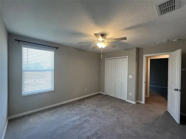 an empty room with closet and a chandelier fan