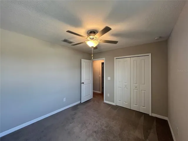 an empty room with windows and chandelier fan