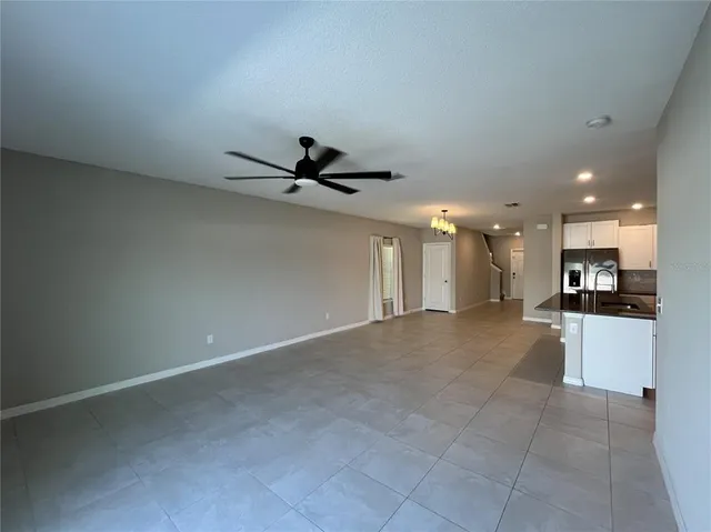 a view of a livingroom with a ceiling fan & kitchen floor