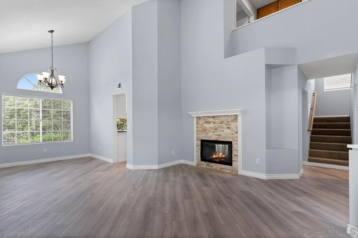 13948 Carmel Ridge Road San Diego, CA 92128 - Photo 4 of 26 a view of an empty room with wooden floor fireplace and a window