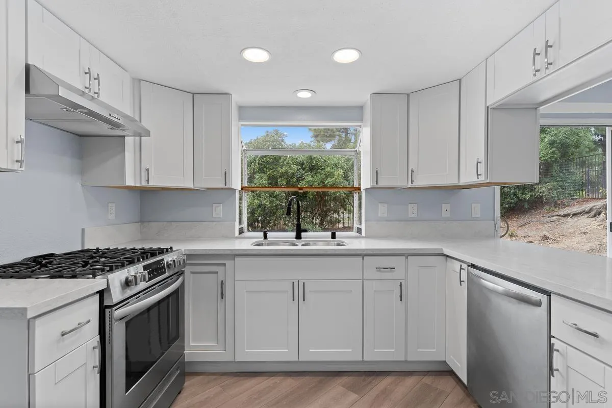 13948 Carmel Ridge Road San Diego, CA 92128 - Photo 7 of 26 a kitchen with white cabinets appliances a sink and a window