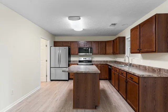 a kitchen with stainless steel appliances granite countertop a stove sink refrigerator and cabinets