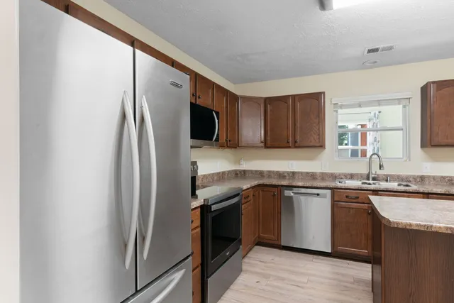 a kitchen with stainless steel appliances granite countertop a refrigerator and a sink