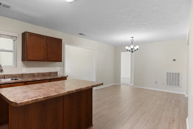 a kitchen with granite countertop a sink cabinets and wooden floor