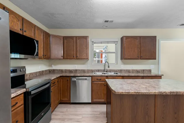 a kitchen with stainless steel appliances granite countertop a sink stove and microwave