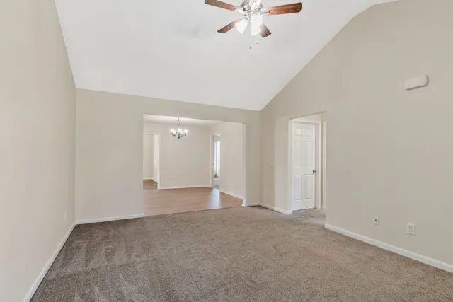 an empty room with a ceiling fan and carpet