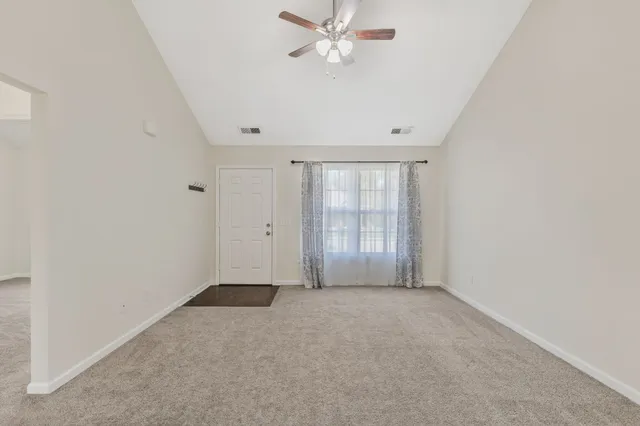 an empty room with windows and fan