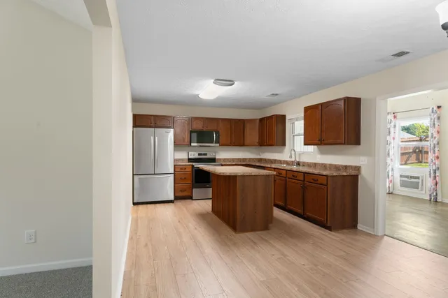 a large kitchen with stainless steel appliances granite countertop a stove a sink dishwasher and a refrigerator with wooden floor