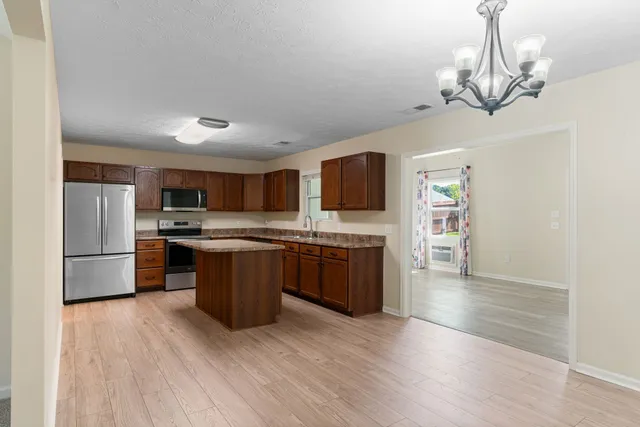 a large kitchen with a wooden floor and stainless steel appliances