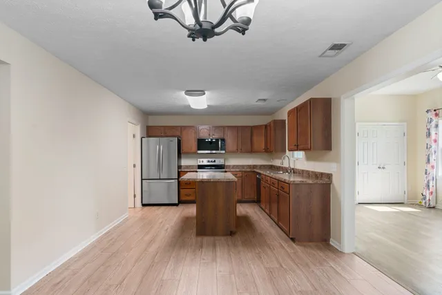 a kitchen with kitchen island granite countertop a sink cabinets and stainless steel appliances