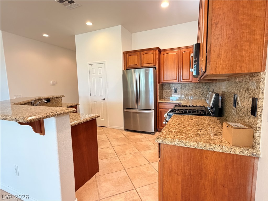 16 Caprington Road Henderson, NV 89052 - Photo 4 of 16 Granite countertops and rich wood cabinetry anchor this open culinary workspace.