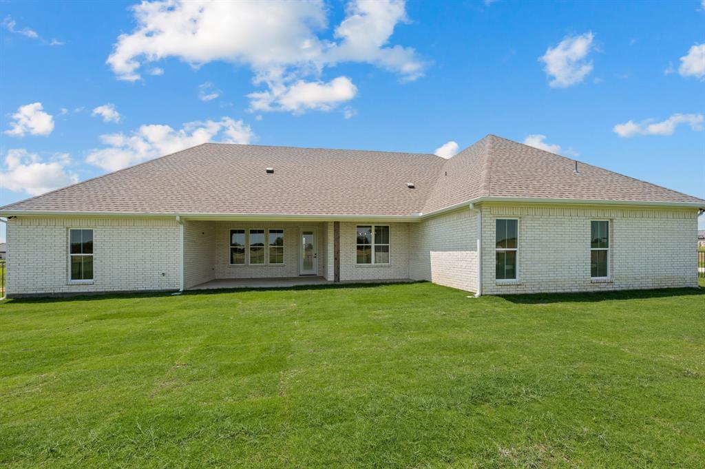 2705 Gospel Road Tolar, TX 76476 - Photo 30 of 36 Expansive backyard featuring a manicured lawn, white brick exterior, covered patio, and multiple windows providing natural light