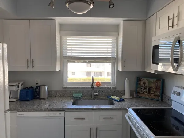a kitchen with granite countertop a sink a window and cabinets