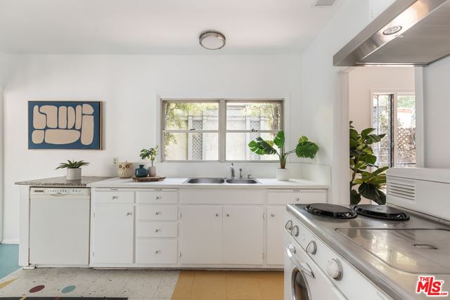 a kitchen with granite countertop a sink stainless steel appliances white cabinets and a window