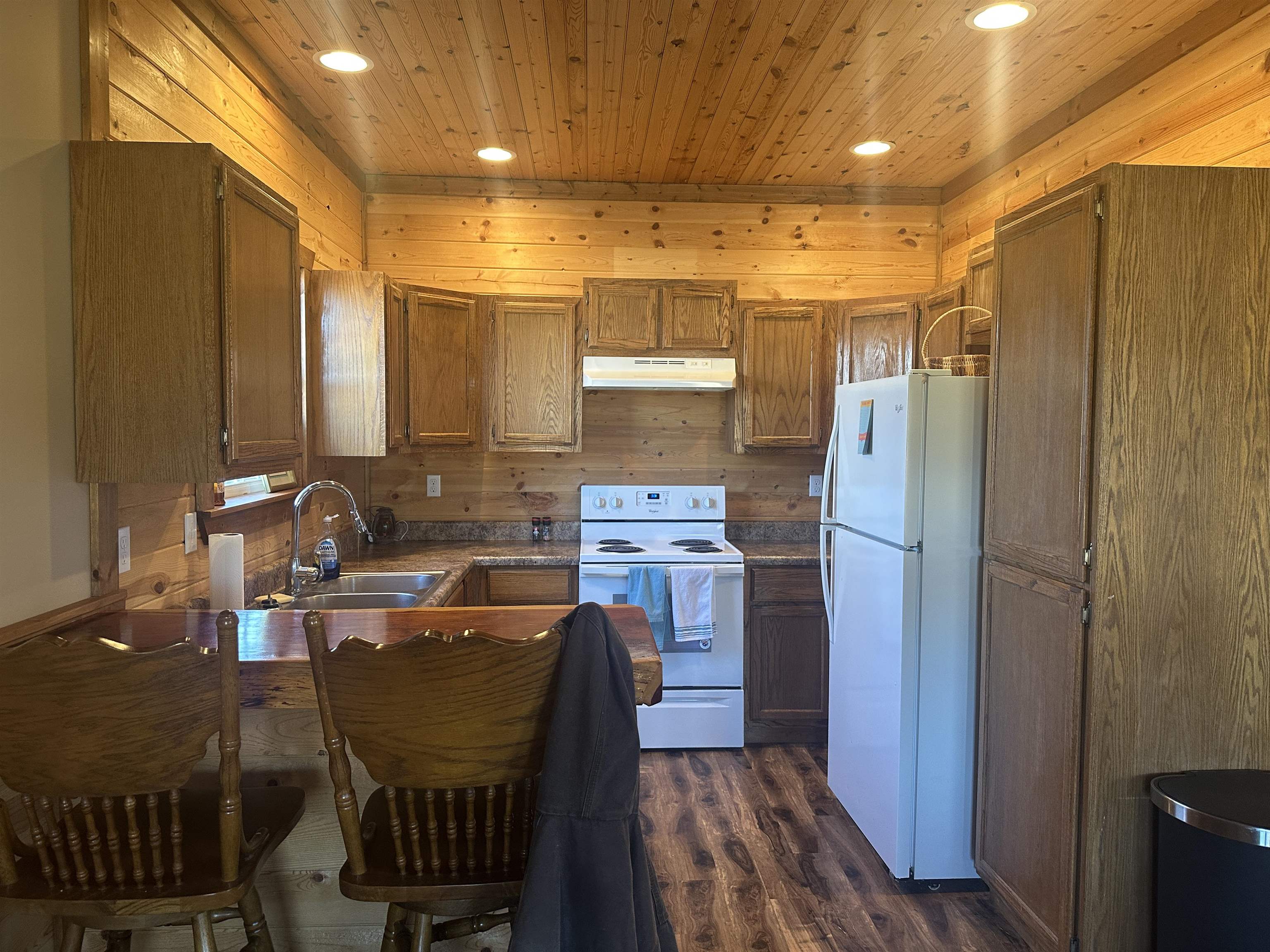 2245 Fritton Spur Road Middleton, TN 38052 - Photo 15 of 24 Kitchen featuring white appliances, wood walls, brown cabinetry, dark wood-style flooring, and dark countertops