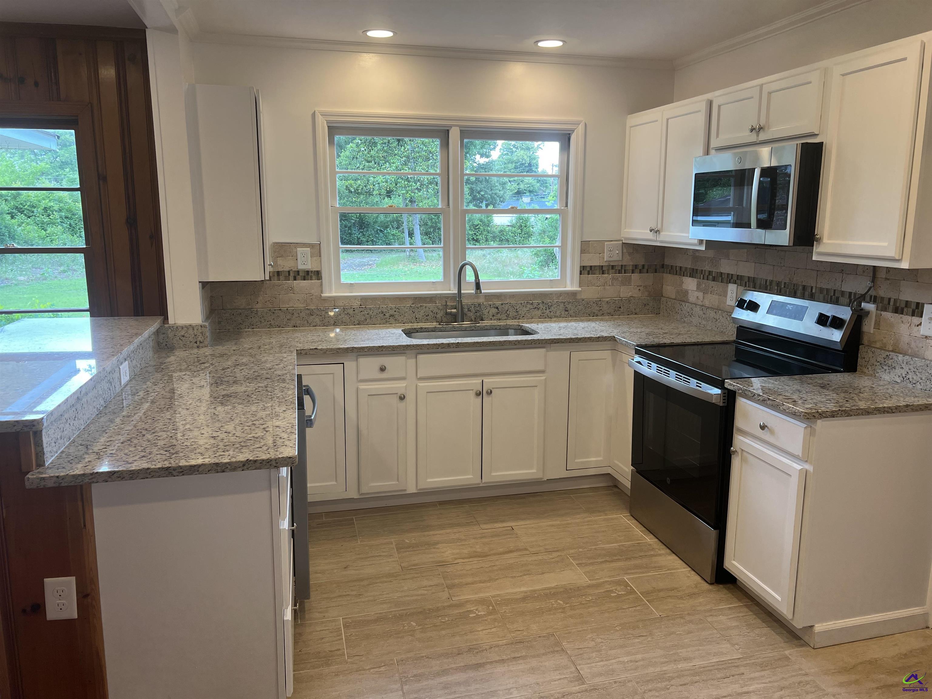 145 South 2nd Street Cochran, GA 31014 - Photo 4 of 24 a kitchen with stainless steel appliances granite countertop a sink a stove a microwave a counter space and cabinets