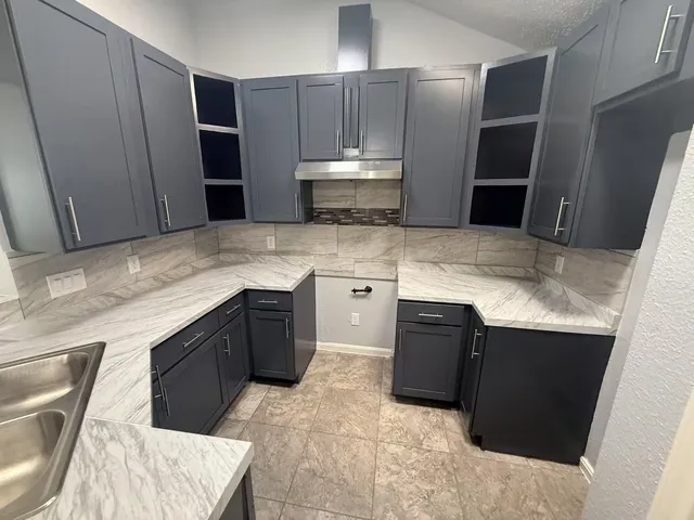 a kitchen with stainless steel appliances granite countertop wooden cabinets a refrigerator and a sink
