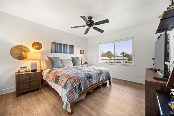 a bedroom with a bed and dresser with wooden floor